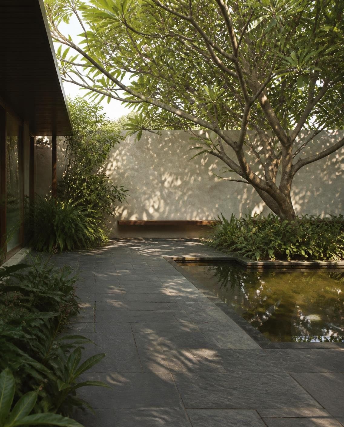 Illustrative courtyard garden with stone paving, a reflecting pool and a frangipani tree